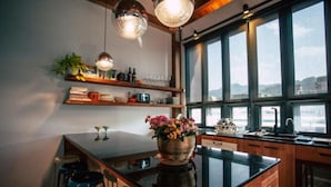 A modern kitchen with a large island, pendant lighting, and a view through large windows. - Sweethome37 (New Taipei City)