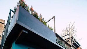 A modern building with a blue facade, large windows, and a balcony with plants. - Sweethome37 (New Taipei City)