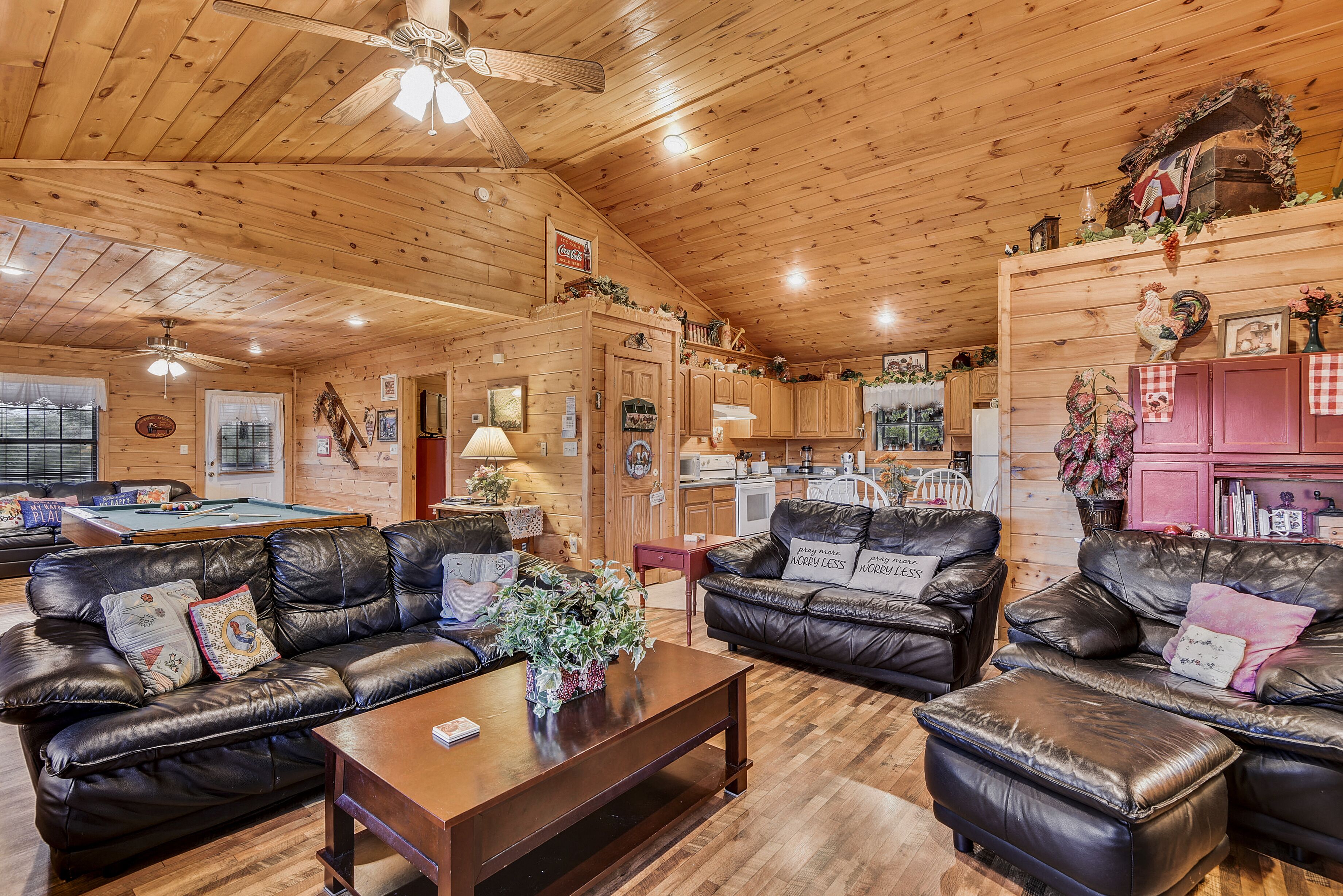 Un intérieur de chalet chaleureux avec une table de billard, des canapés en cuir et un coin cuisine.