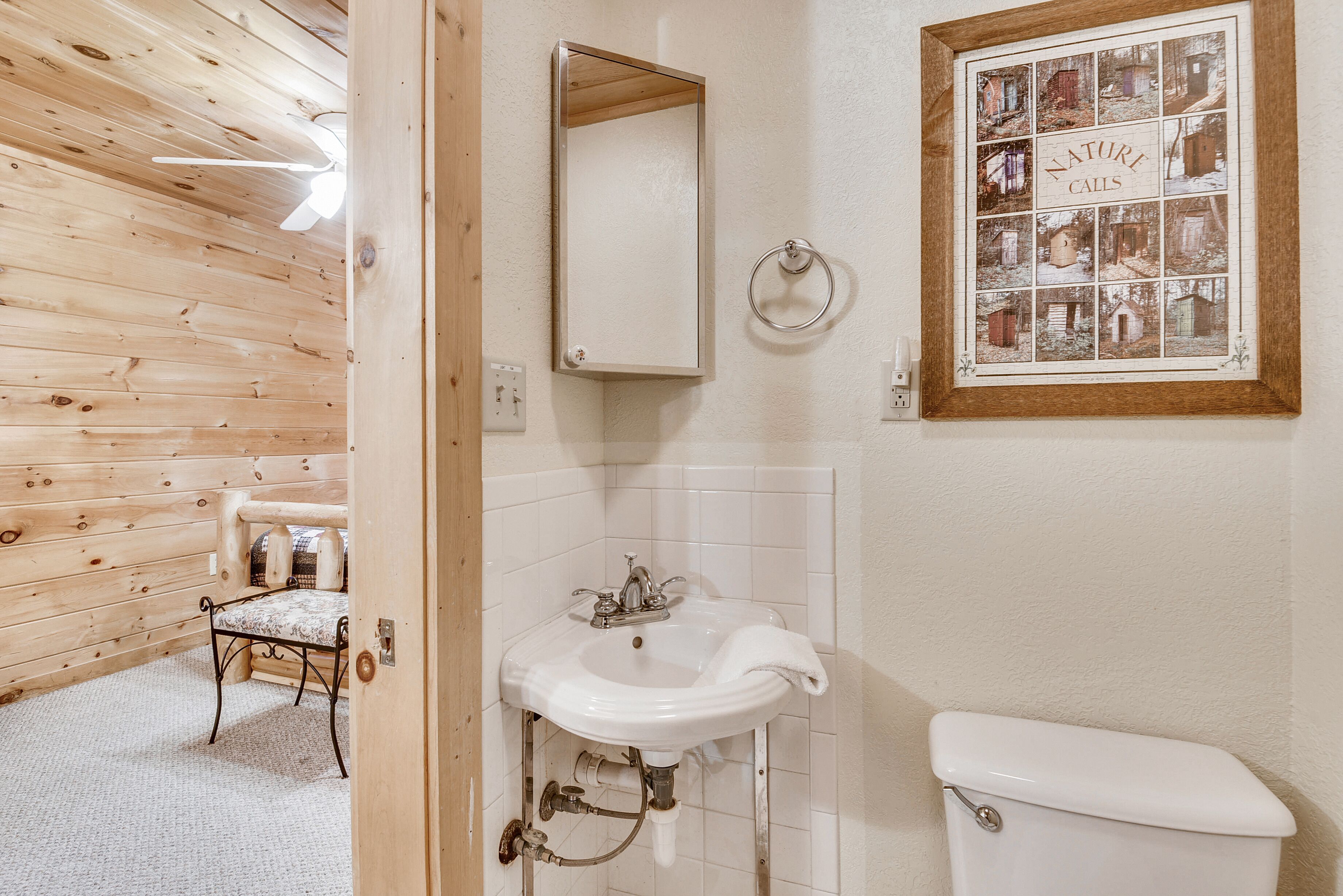 A bathroom with a wooden interior, a white sink, a mirror, and a toilet.