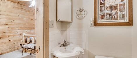 A bathroom with a wooden interior, a white sink, a mirror, and a toilet.