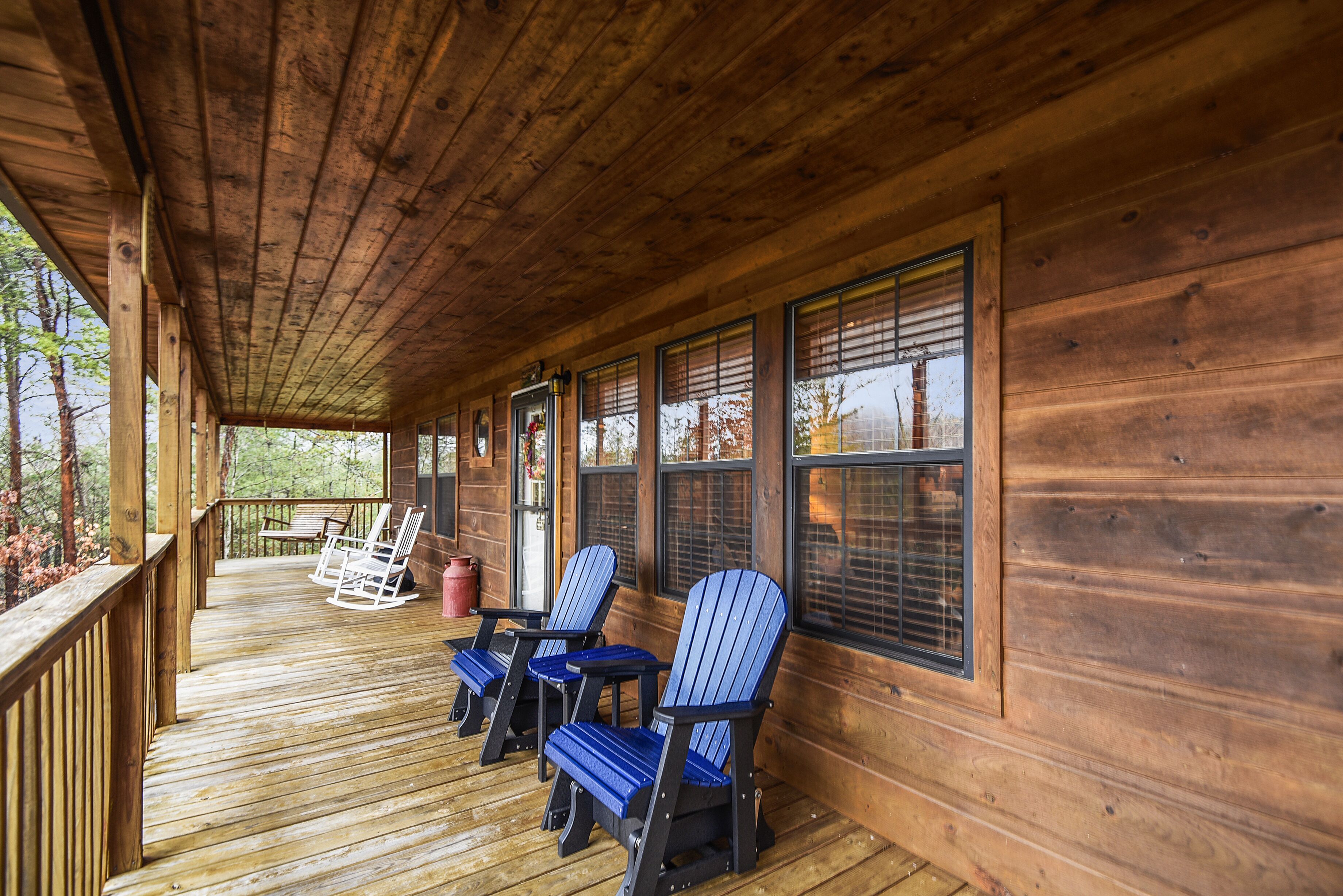 Eine Holzterrasse mit Schaukelstühlen und einem überdachten Bereich.