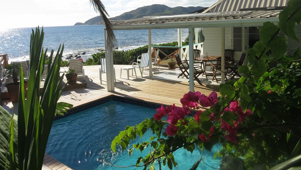 A pool area with lounge chairs, a pergola, and a view of the ocean. - Luxurious Oceanfront Villa with Stunning Views Over Montserrat (Falmouth Harbour)