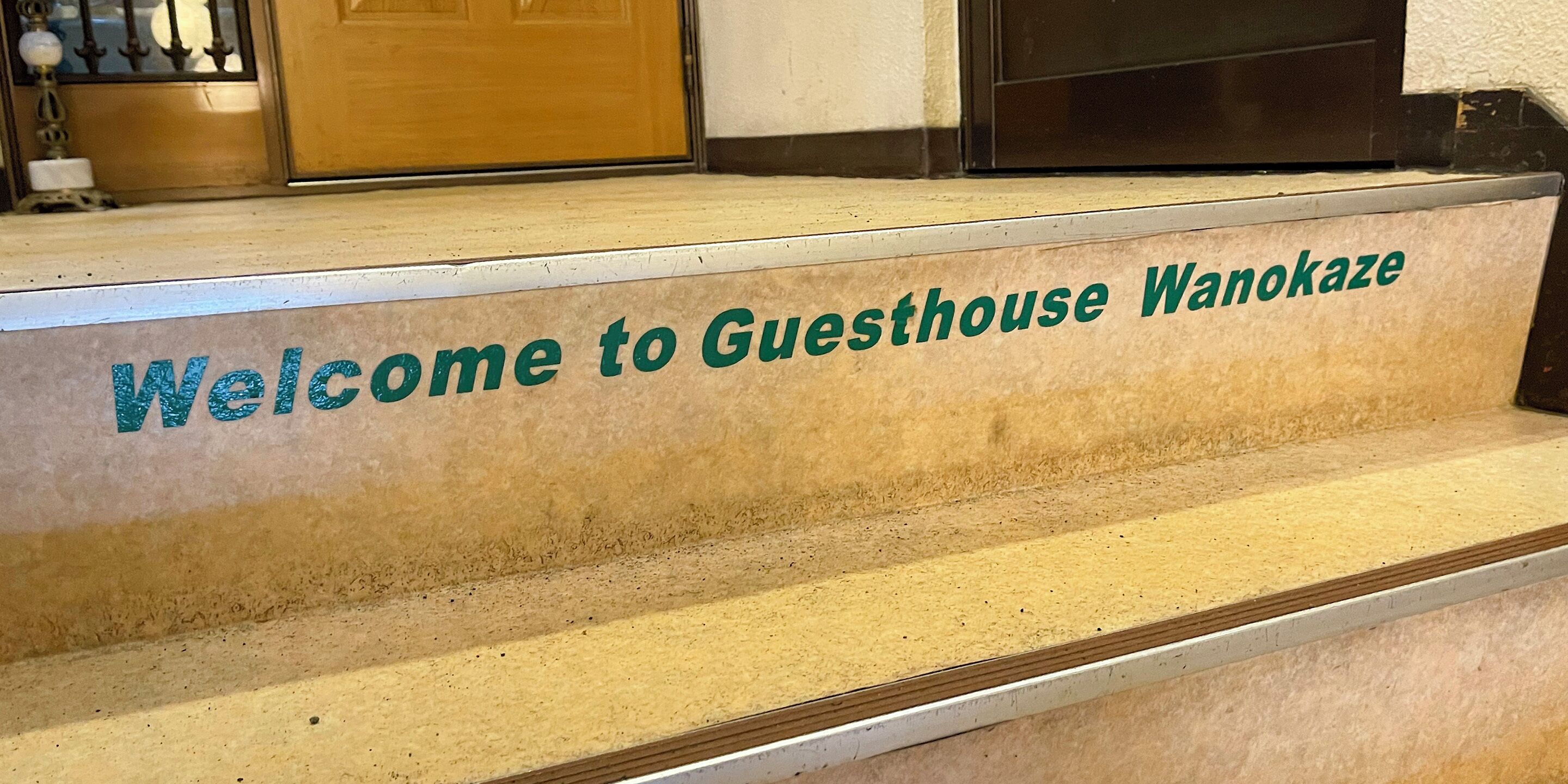 A welcome sign at the entrance of a guesthouse named "Guesthouse Wanokaze."