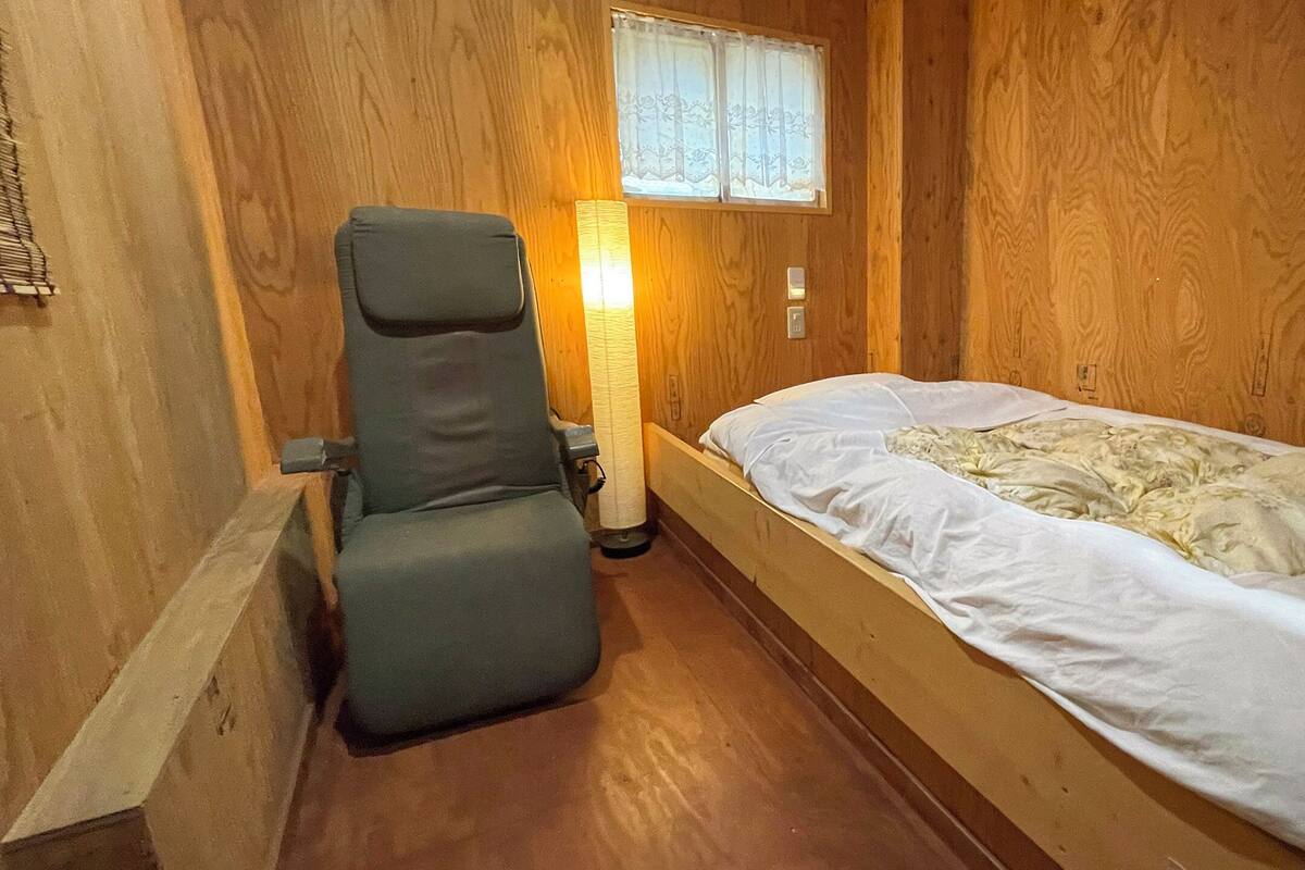 A small, cozy room with a single bed, a chair, and a nightstand.