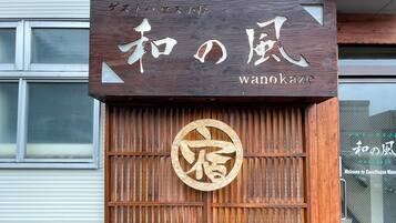 Un letrero de madera con caracteres japoneses y el nombre 'wanokaze' en inglés.