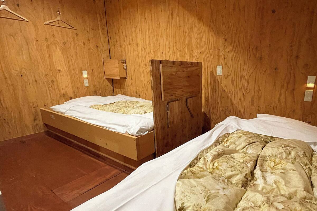 A wooden room with two beds, wooden walls, and a wooden floor.