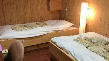 A room with two wooden bunk beds, a desk, and a wall-mounted air conditioner.