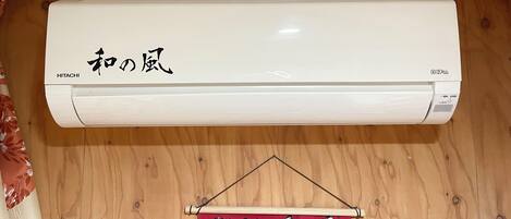 A white air conditioner mounted on a wooden wall with Japanese characters and the brand name "HITACHI".