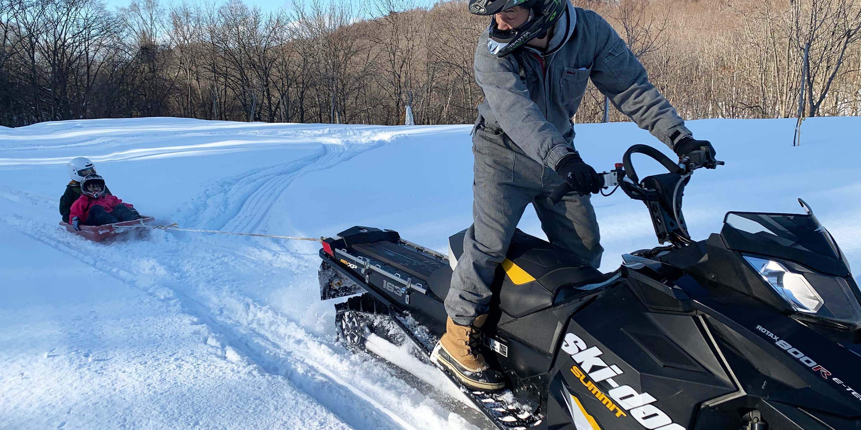 Una persona su un motoslitta con rimorchio, in un ambiente innevato.