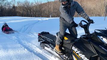 Una persona su un motoslitta con rimorchio, in un ambiente innevato.