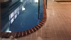 A swimming pool with a tiled deck, a metal ladder, and a tiled wall with a blue stripe. - Guest House Otaru WANOKAZE - Hostel (Otaru)