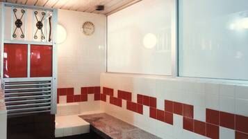 A bathroom with a tiled wall, a clock, and a window.