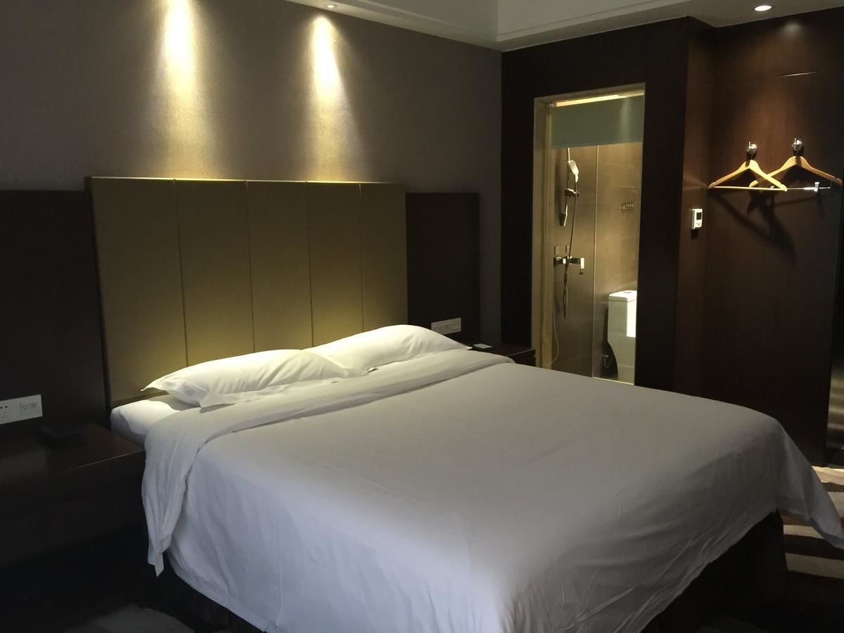 Quarto de hotel com uma cama grande, mesa de cabeceira, guarda-roupa e espelho.