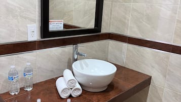 Un baño con un espejo grande, un lavamanos blanco y un revestimiento de mármol.