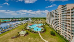 A hotel with multiple balconies, a marina with boats, and a central swimming pool. - Upscale Waterway View Condo, Onsite Golf Course | Yacht Club Villas - 3-303 (North Myrtle Beach)