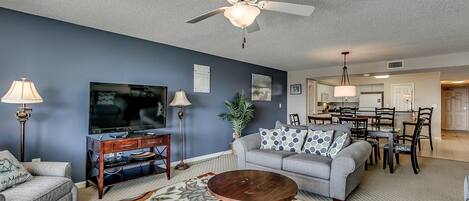 Ein Wohnzimmer mit Deckenventilator, Fernseher, Couchtisch und Sofa.