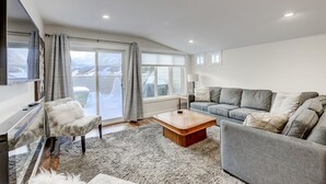 Un salon moderne comprenant un canapé, un fauteuil, une table basse et un téléviseur.