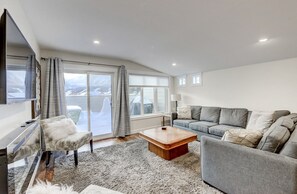 Uma sala de estar moderna com um sofá, poltrona, mesa de centro e uma televisão.