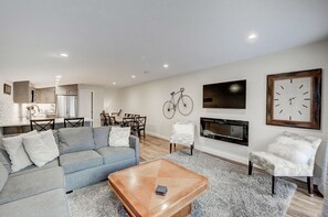 A modern living room with a grey sofa, a wooden coffee table, and a fireplace. - Canmore Townhouse! Jaw-dropping views and walk to Downtown (Canmore)