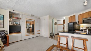 Una cocina pequeña equipada con microondas, refrigerador y taburetes de madera.