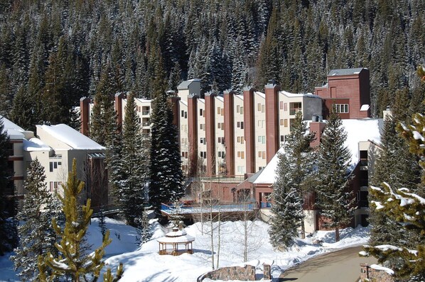 A multi-story hotel with a central courtyard, surrounded by snow-covered trees and a clear sky.