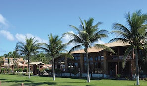 A resort with multiple buildings, palm trees, and a well-maintained lawn.