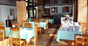 Ein Restaurant mit Holztischen und -stühlen, einer Ziegelwand und einer Theke mit Lebensmitteln.