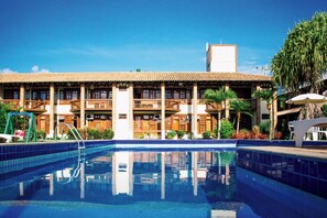 Un hotel con piscina, varios balcones y un cielo azul despejado.
