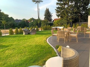 An outdoor patio area with wicker furniture and a well-maintained lawn.
