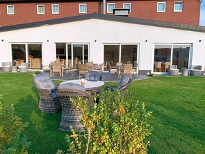 A building with a flat roof, large glass doors, and outdoor wicker furniture.