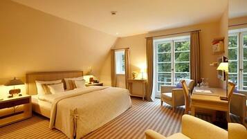 A hotel room with a large bed, a desk with a chair, and a window with curtains.