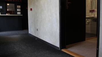 Un couloir avec un comptoir d’accueil portant l’inscription « RÉCEPTION » et des toilettes visibles à travers une porte ouverte.