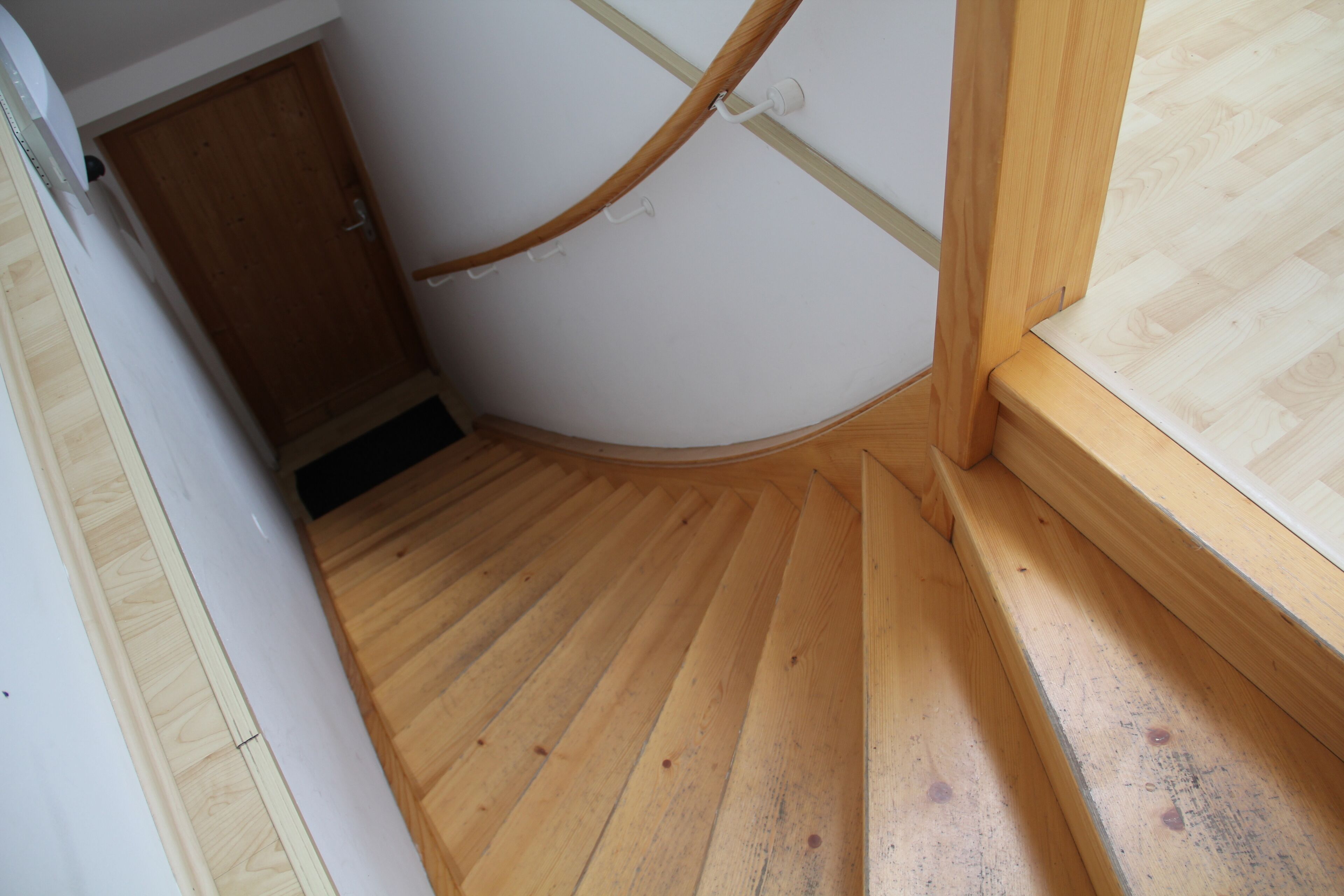 Un escalier en bois menant à une porte, un plancher en bois et une fenêtre avec un cadre en bois.