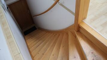 Un escalier en bois menant à une porte, un plancher en bois et une fenêtre avec un cadre en bois.