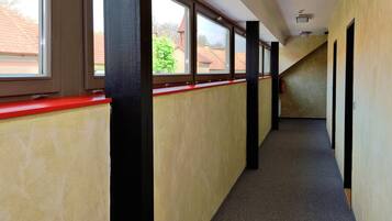 A corridor with a red-tinted window ledge, beige walls, and a carpeted floor.