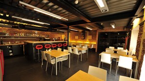 A modern bar with a brick wall, wooden tables, and white chairs. - Hotel U Tri volu (Býkovice)