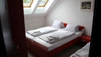 Ein Schlafzimmer mit zwei Betten, einem Dachfenster, einer Heizung, einem Nachttisch und einem gerahmten Bild an der Wand.