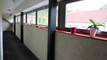 Un pasillo con ventanas, un alféizar rojo y una planta en maceta.