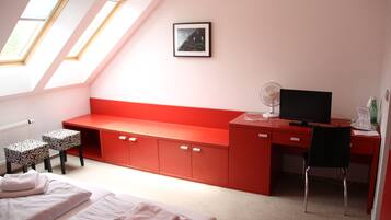 A bedroom with a bed, a desk, a chair, a radiator, and a window.