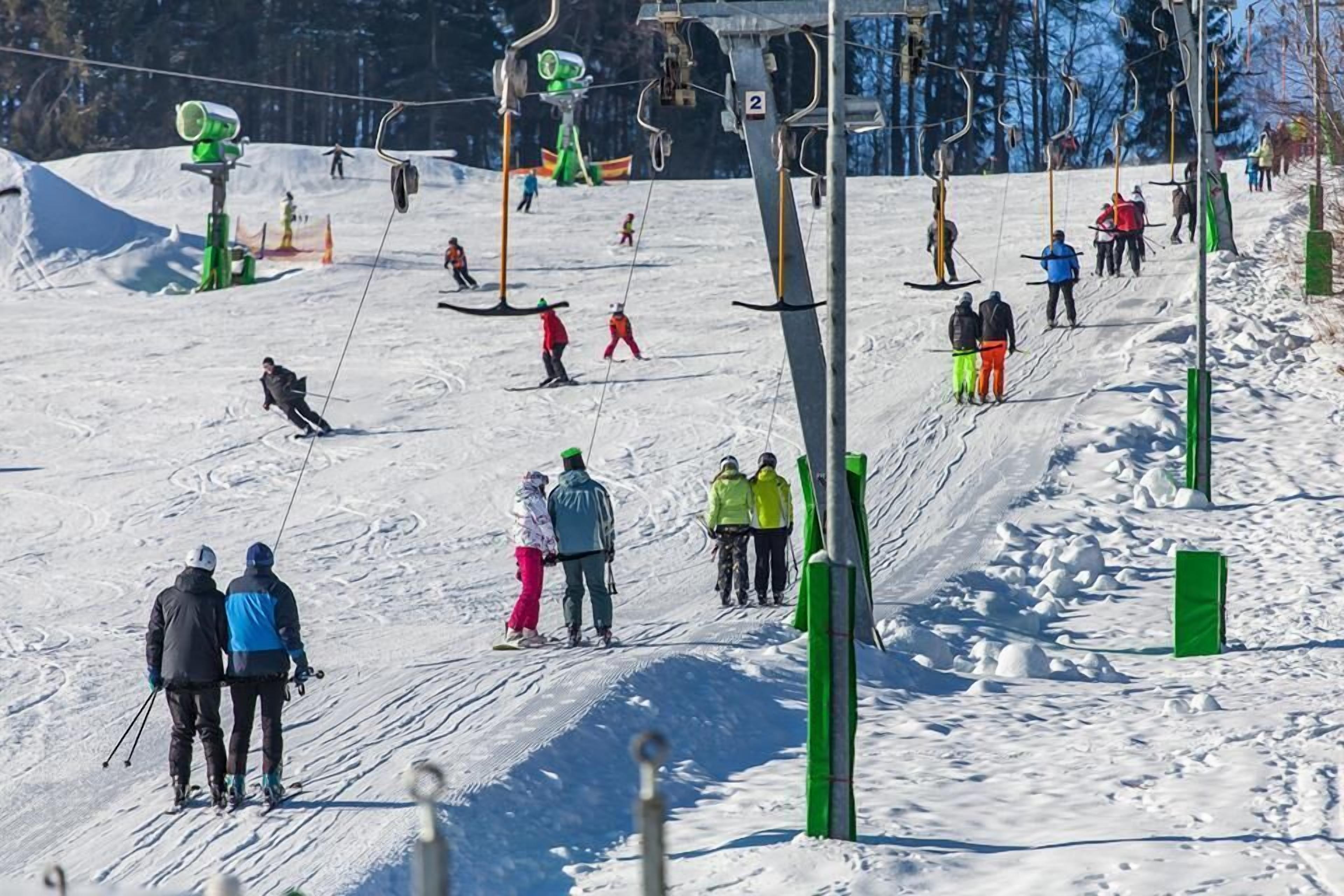 Pendenza per sci con sciatori e snowboarder, impianti di risalita e reti di protezione verdi.
