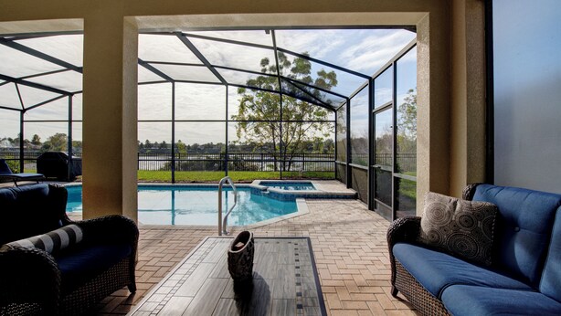 Un espacio al aire libre cubierto con piscina, mobiliario de mimbre y vistas al exterior.