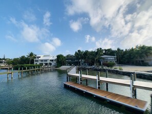A waterfront property with a dock extending into the water, surrounded by lush greenery and palm trees.