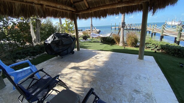 Une terrasse couverte avec vue sur la mer, un hamac et un barbecue.