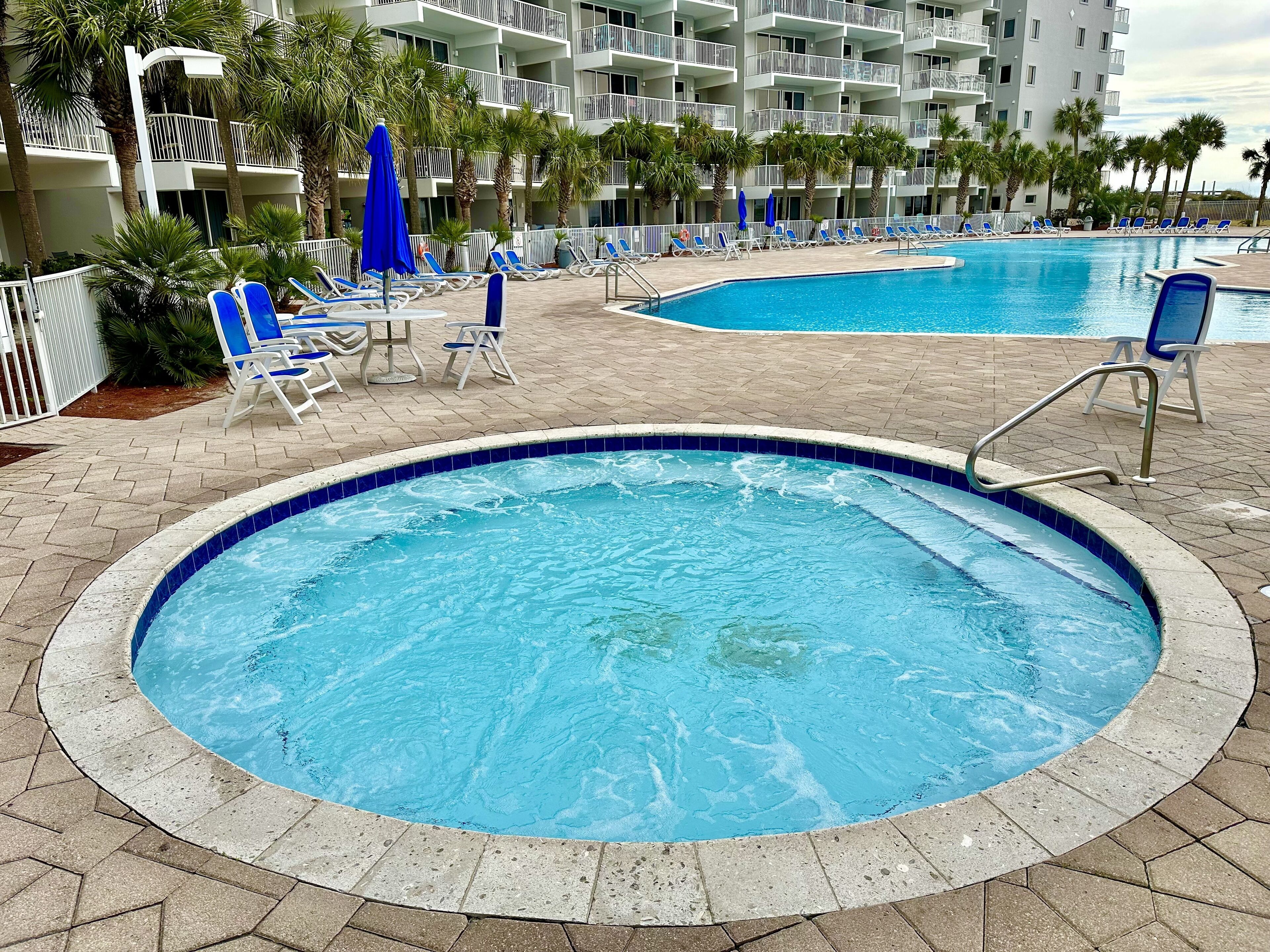 Ein Hotelpoolbereich mit mehreren Pools, Liegestühlen und Palmen.