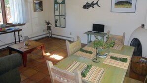 A dining area with a table set for two, a television on a stand, and a window with curtains.