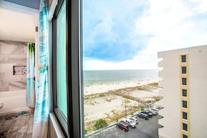 A room with a view of a beach and parking area.