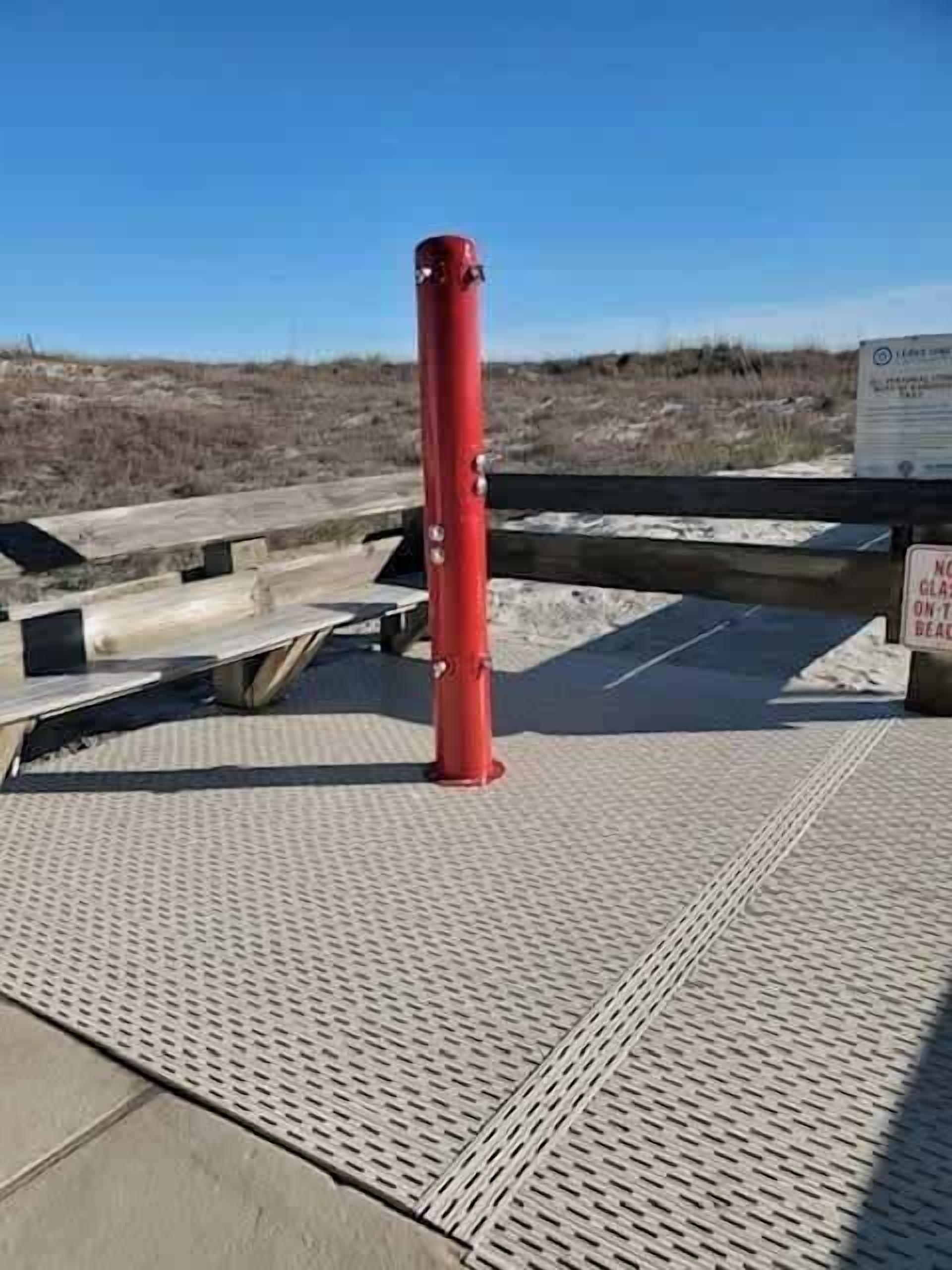 A red bollard on a textured metal deck with a sign in the background.