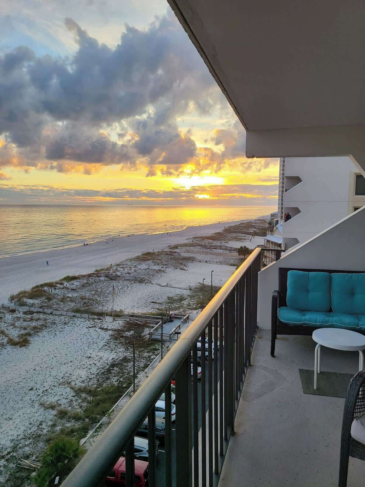 A balcony with a view of the beach and sunset.
