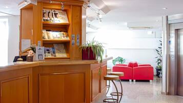 Ein Empfangsbereich mit einem Holzbüro, einem roten Teppich und einer roten Couch im Hintergrund.